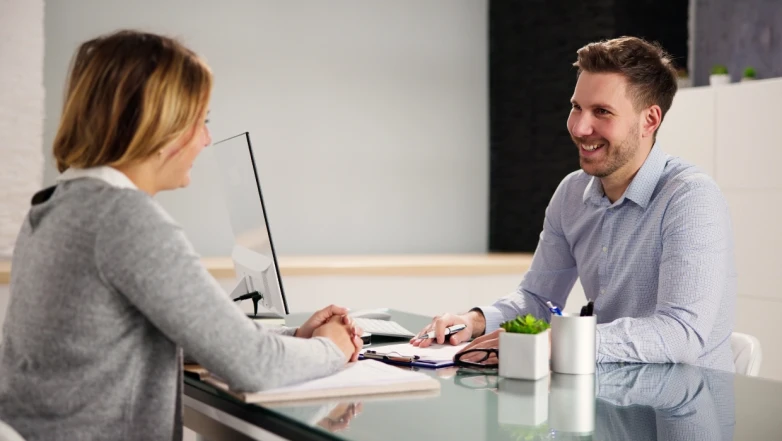 Un manager et une collaboratrice échangent lors d’un entretien annuel, assis face à face dans un bureau lumineux, illustrant un dialogue constructif et un leadership partagé.